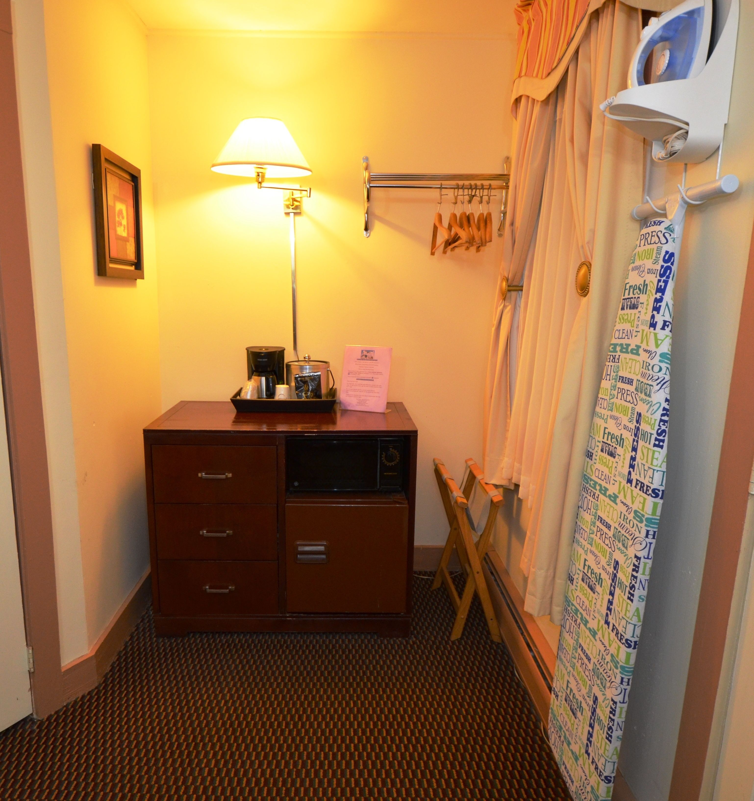 Une chambre d’hôtel équipée d’un bureau, d’une lampe, d’un rideau de douche orné de motifs et d’un porte-serviettes.