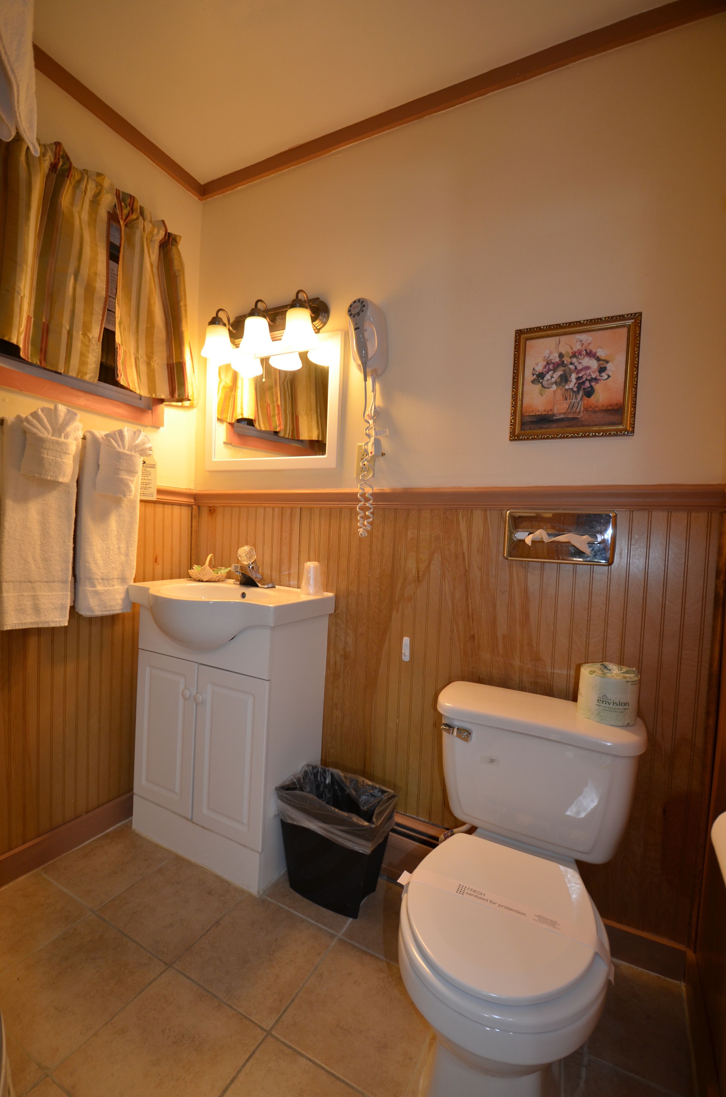 A bathroom with a sink, toilet, and a trash bin.