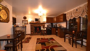 A kitchen with a fireplace, dining area, and a large window with curtains. - Williamstown Motel (Williamstown)