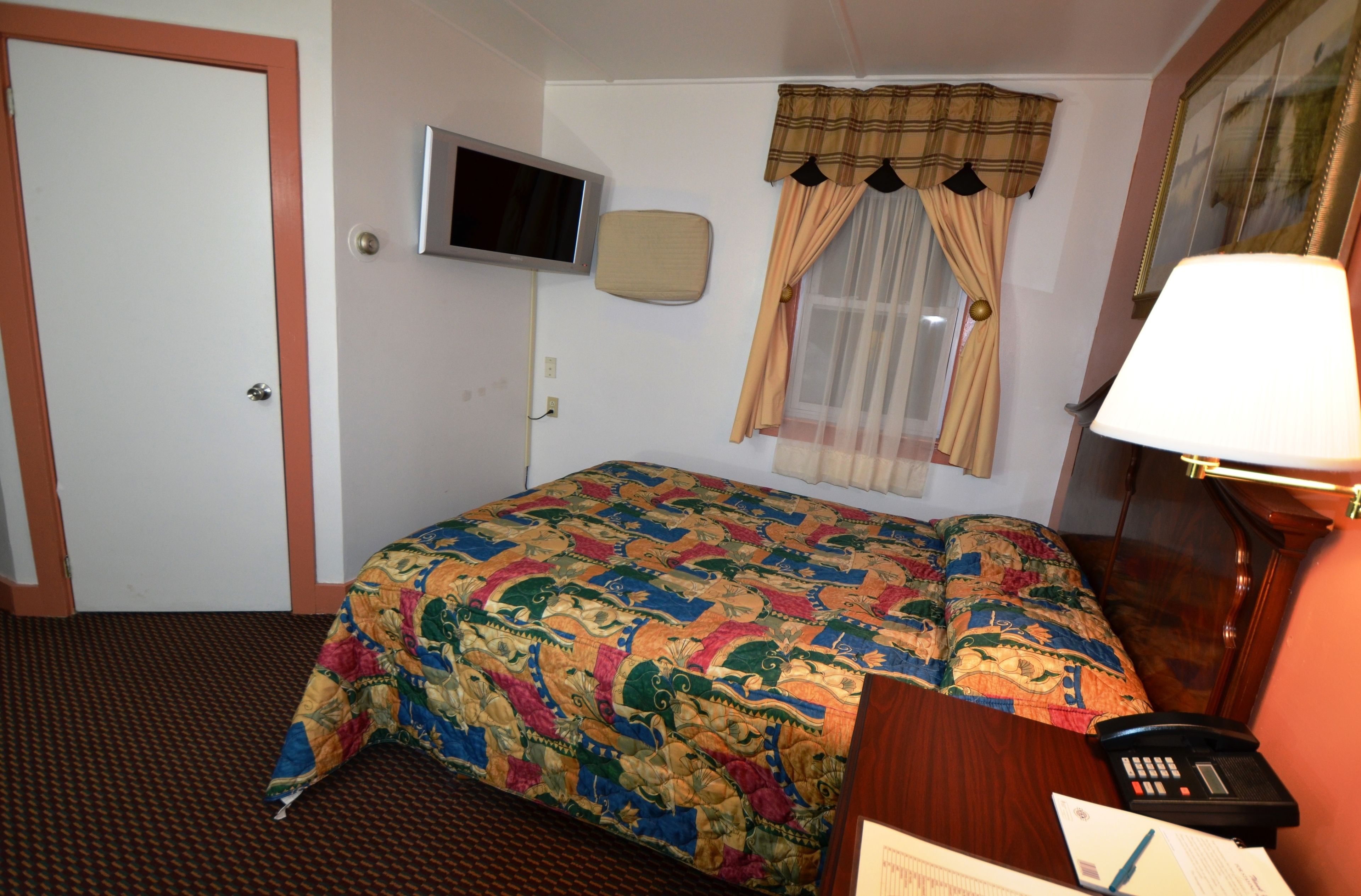 Ein Hotelzimmer mit Bett, Fernseher, Telefon und Lampe.