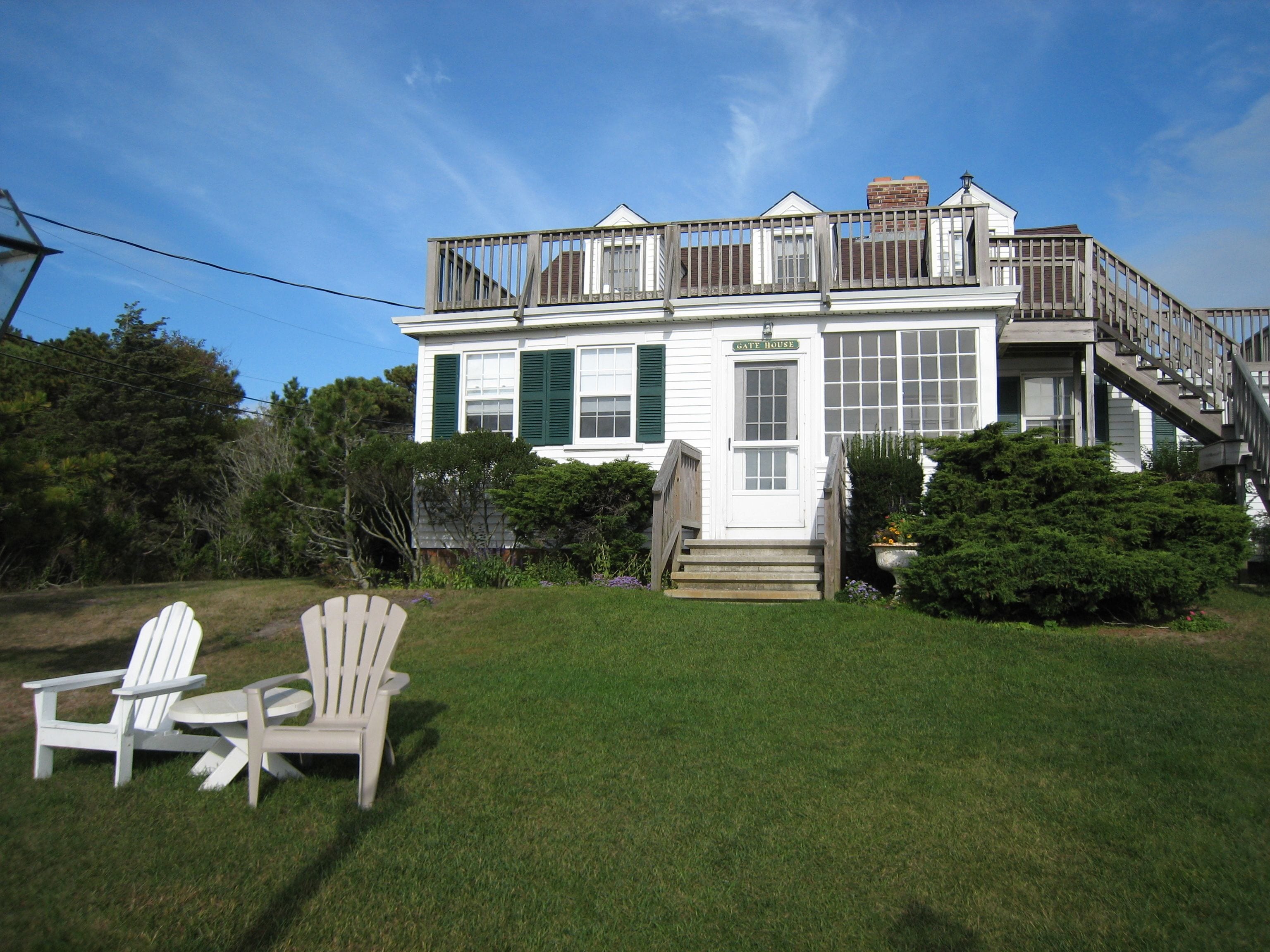 Une maison à deux étages avec un porche à l’avant, un escalier et une terrasse.