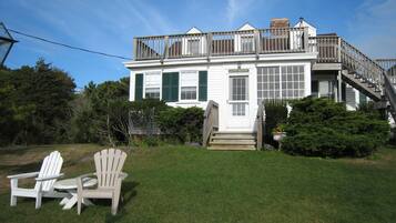 Une maison à deux étages avec un porche à l’avant, un escalier et une terrasse.