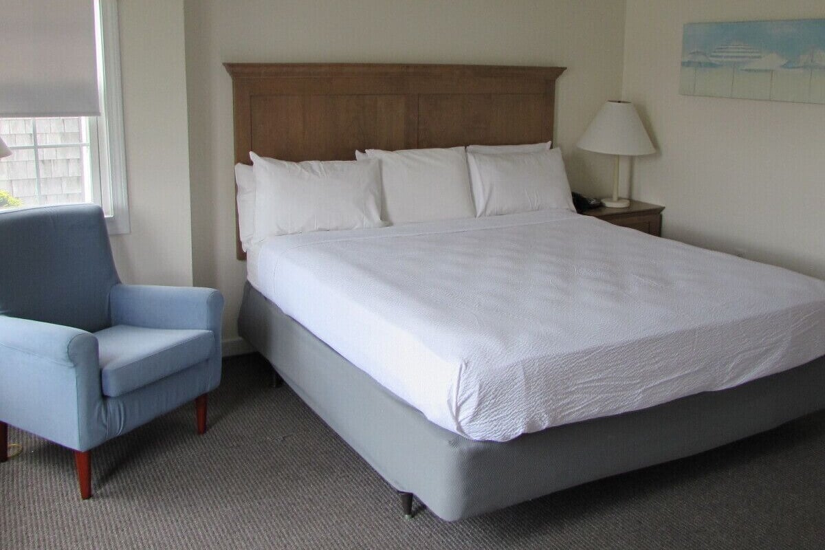 Una habitación de hotel con una cama, una silla, una mesita de noche y una ventana.