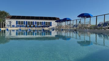 Una piscina al aire libre de temporada, sillones reclinables de piscina