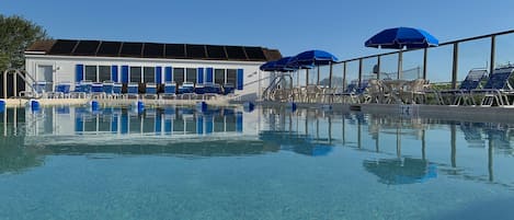 Una piscina al aire libre de temporada, sillones reclinables de piscina