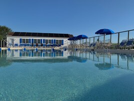 Una piscina al aire libre de temporada, sillones reclinables de piscina