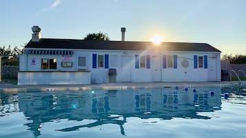 Un edificio con piscina, una caseta de socorrista y un letrero que advierte que no hay salvavidas de servicio.