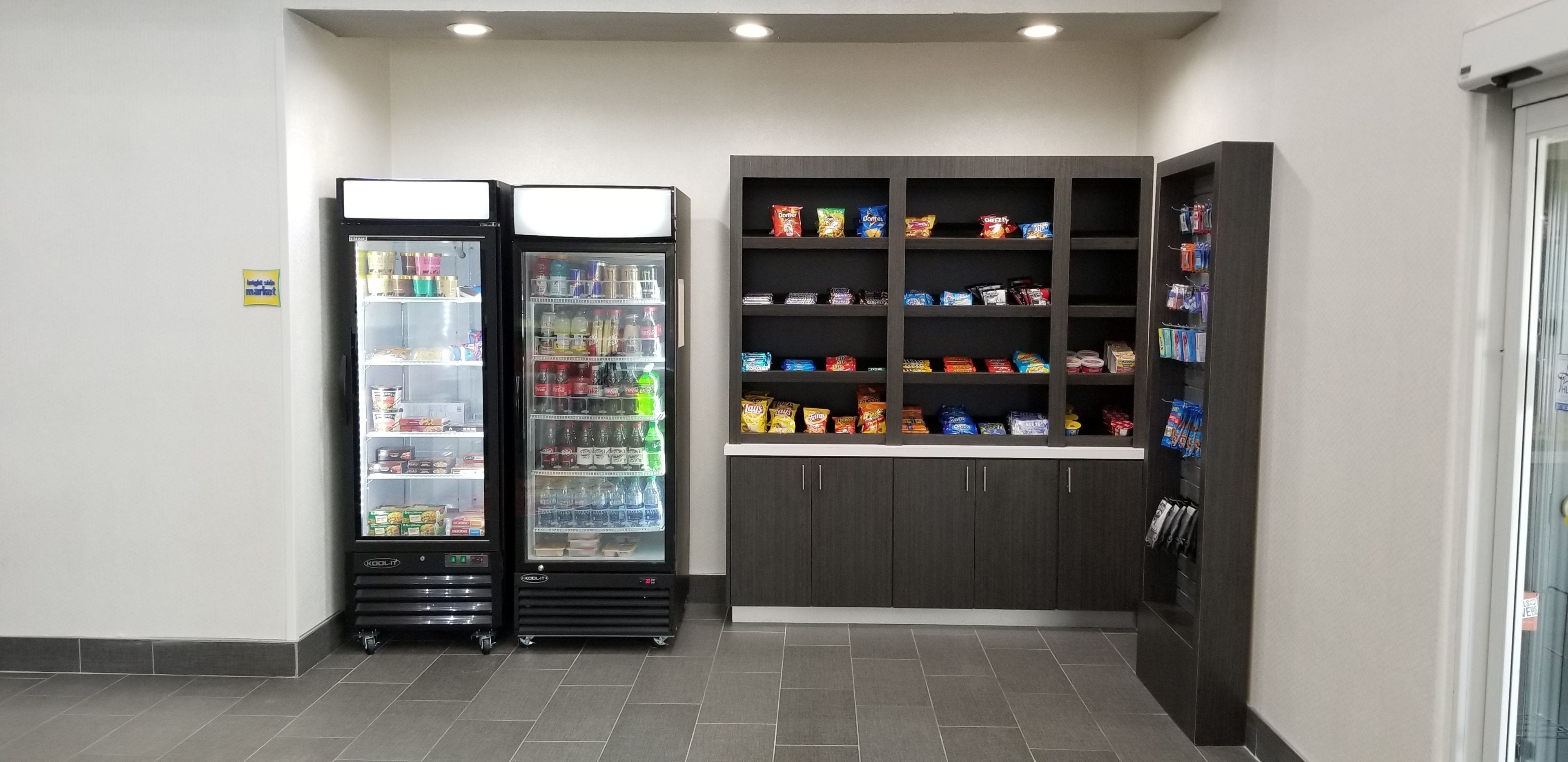 A vending area with two refrigerated beverage dispensers and a shelf stocked with snacks.
