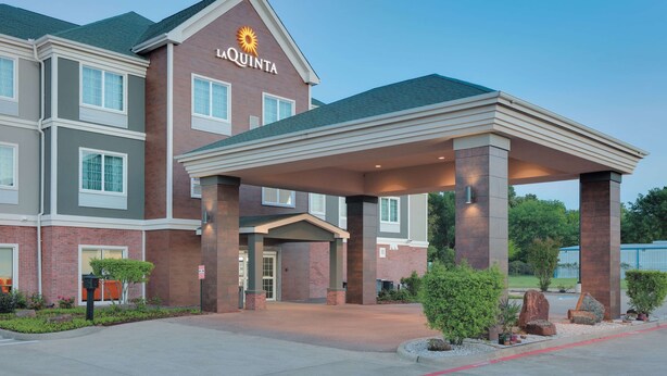 A hotel entrance with a covered patio, brick facade, and a sign reading "La Quinta". - La Quinta Inn & Suites by Wyndham Tyler South (Tyler)