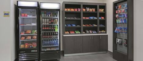A vending area with snack and drink options, including a refrigerated section and a shelf with packaged goods.