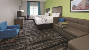 A hotel room with a bed, two armchairs, a sofa, a TV, a desk, and a framed picture on the wall. - La Quinta Inn & Suites by Wyndham Tyler South (Tyler)