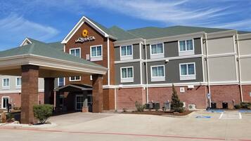 A hotel with a brown facade, a prominent 'La Quinta' sign, and a covered entrance area.