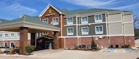A hotel with a brown facade, a prominent 'La Quinta' sign, and a covered entrance area.