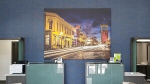 A modern reception area with a unique ceiling light, a large cityscape painting, and contemporary seating. - La Quinta Inn & Suites by Wyndham Tyler South (Tyler)