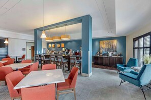 A modern hotel lobby with a bar area, seating arrangements, and artwork on the walls. - Comfort Inn & Suites Brighton Denver NE Medical Center (Brighton)