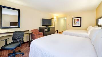 A hotel room with two beds, a desk with a chair, a television, and a mirror.