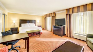 A hotel room with a bed, desk, chair, TV, and a large window with curtains. - Hampton Inn Suites Scottsboro (Scottsboro)