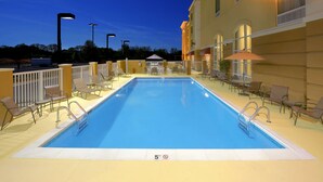 A rectangular outdoor swimming pool with a 5-foot no diving sign, surrounded by lounge chairs and umbrellas, with a building in the background. - Hampton Inn Suites Scottsboro (Scottsboro)