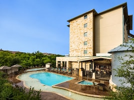 A hotel with a swimming pool, outdoor seating, and a stone building.