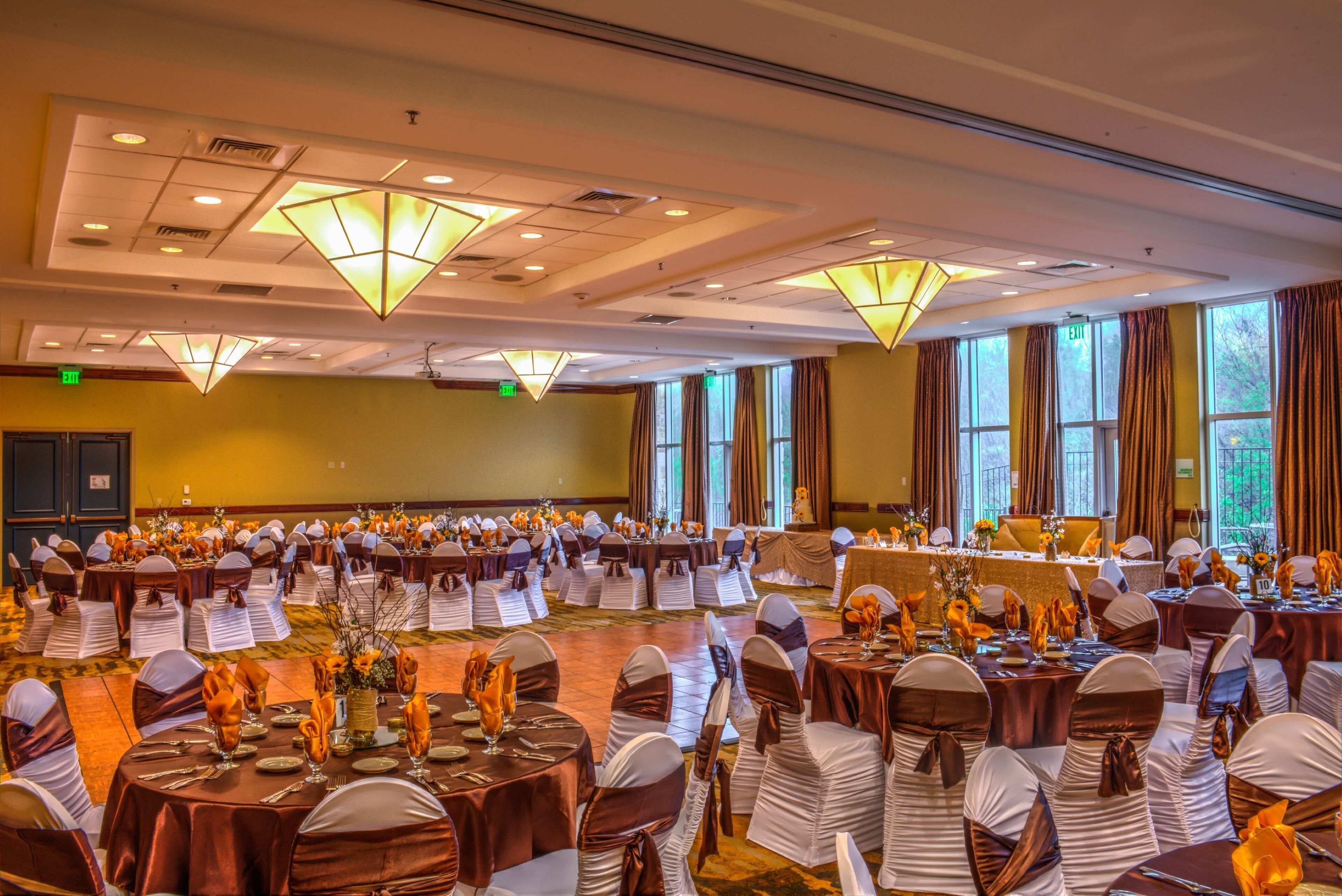 Une salle de banquet avec des tables rondes, des chaises et un éclairage suspendu.