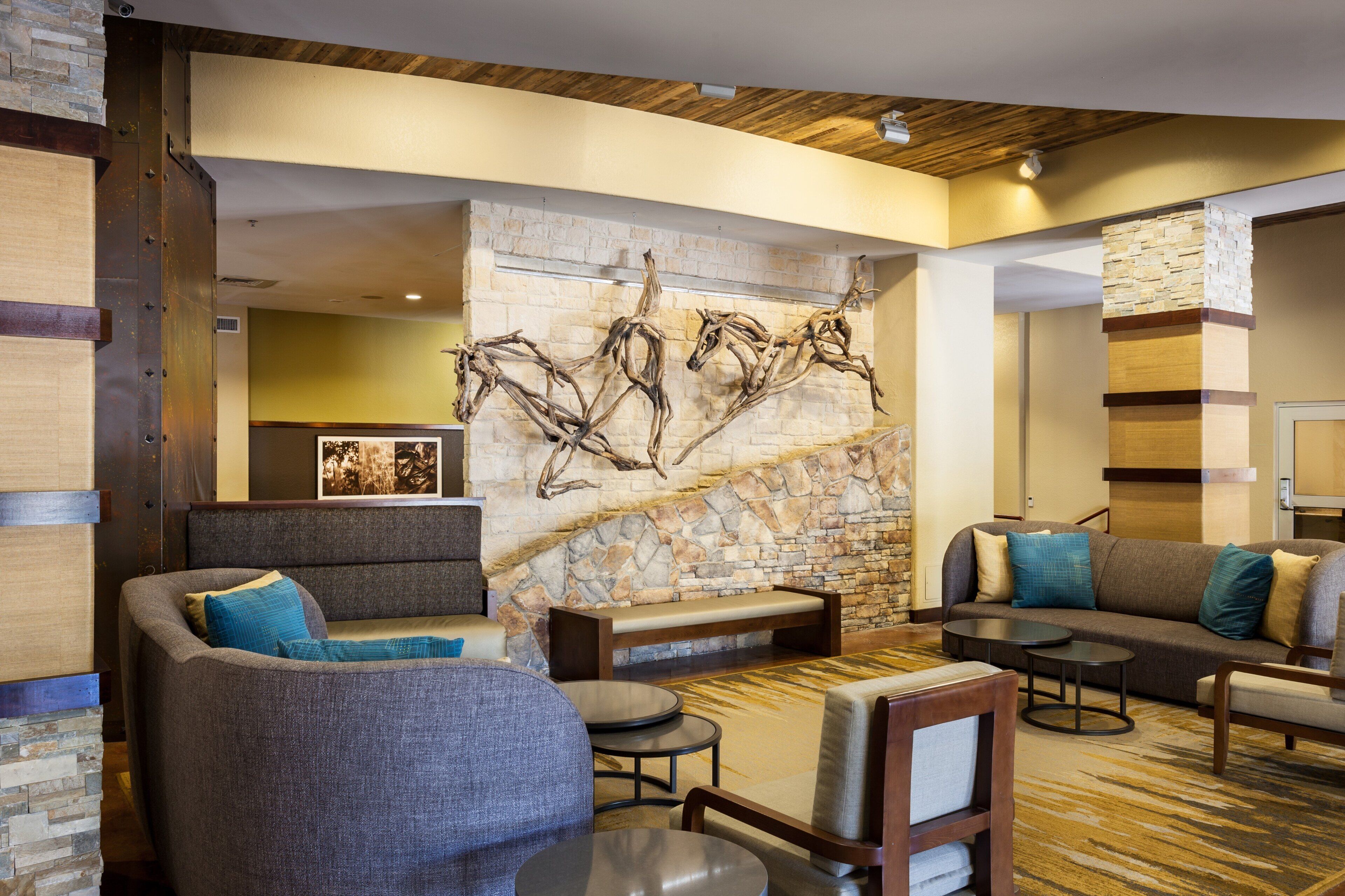 Un vestíbulo de hotel moderno con pared de piedra, zona de estar y techo de madera.