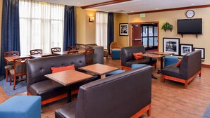 A hotel lobby with leather seating, wooden tables, and a flat-screen TV on the wall. - Hampton Inn Evanston (Evanston)