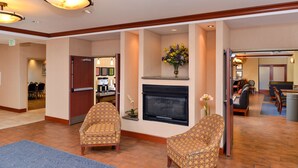 A lobby with two patterned armchairs, a fireplace, and a dining area in the background. - Hampton Inn Evanston (Evanston)