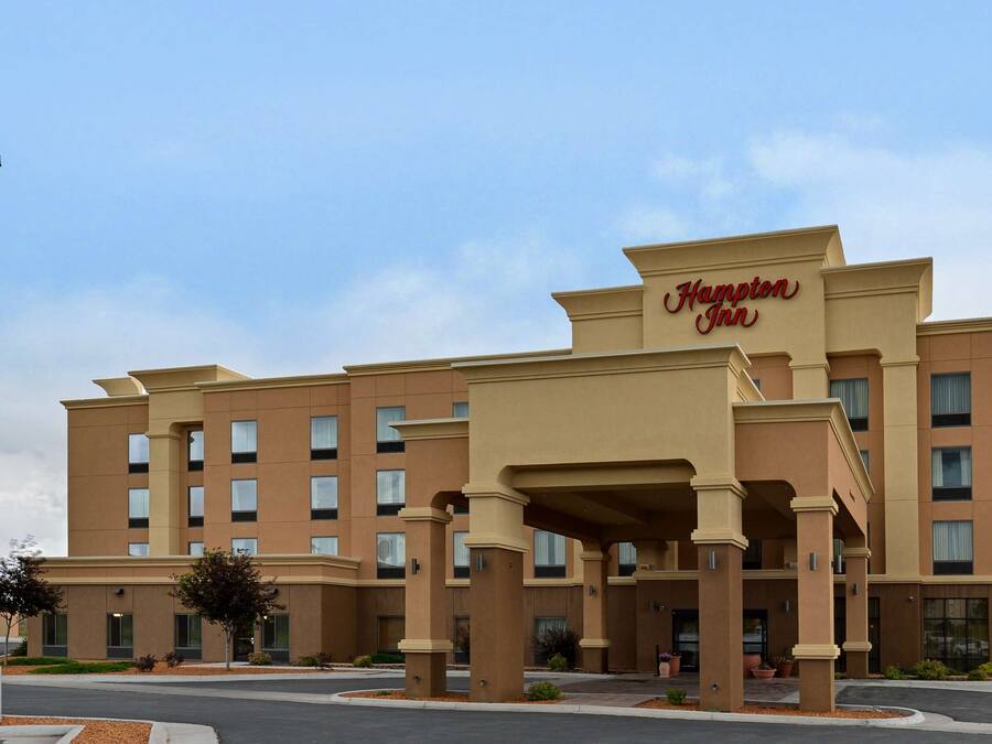 A Hampton Inn hotel with a modern design, featuring a prominent entrance with columns and a large sign.
