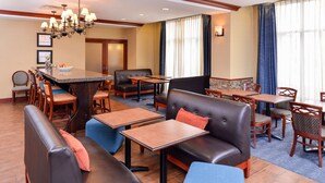 A hotel lobby with a bar area, seating arrangements, and a large window with curtains. - Hampton Inn Evanston (Evanston)