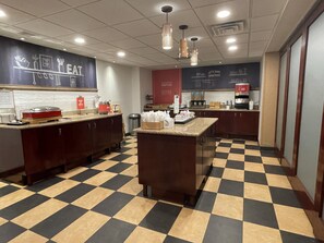 A kitchen area with checkered flooring, a central island, and various kitchen appliances and utensils.