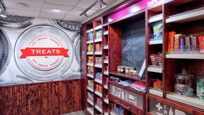 A treats section with shelves stocked with snacks and sweets, a chalkboard with 'Welcome to Rifle, CO' written on it, and a 'Treats' sign above the shelves.