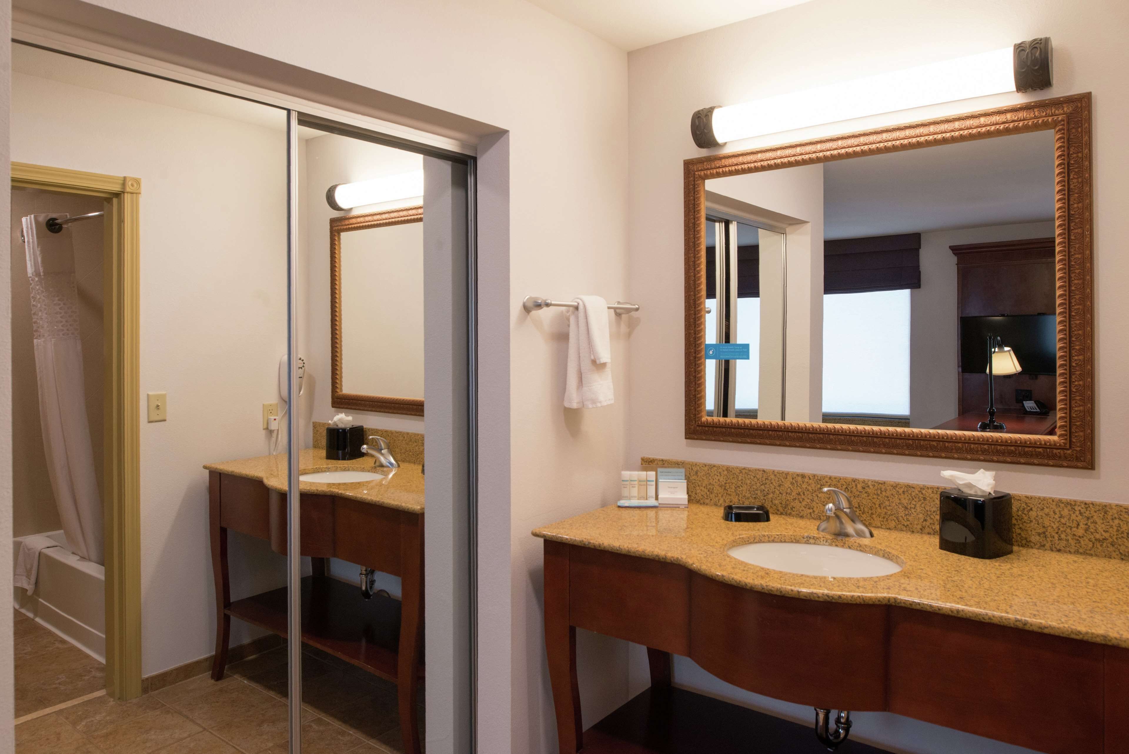 A bathroom with a sink, mirror, and shower.