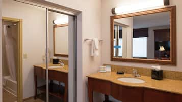 A bathroom with a sink, mirror, and shower.