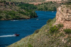 A river with boats, surrounded by green hills and rocky cliffs.