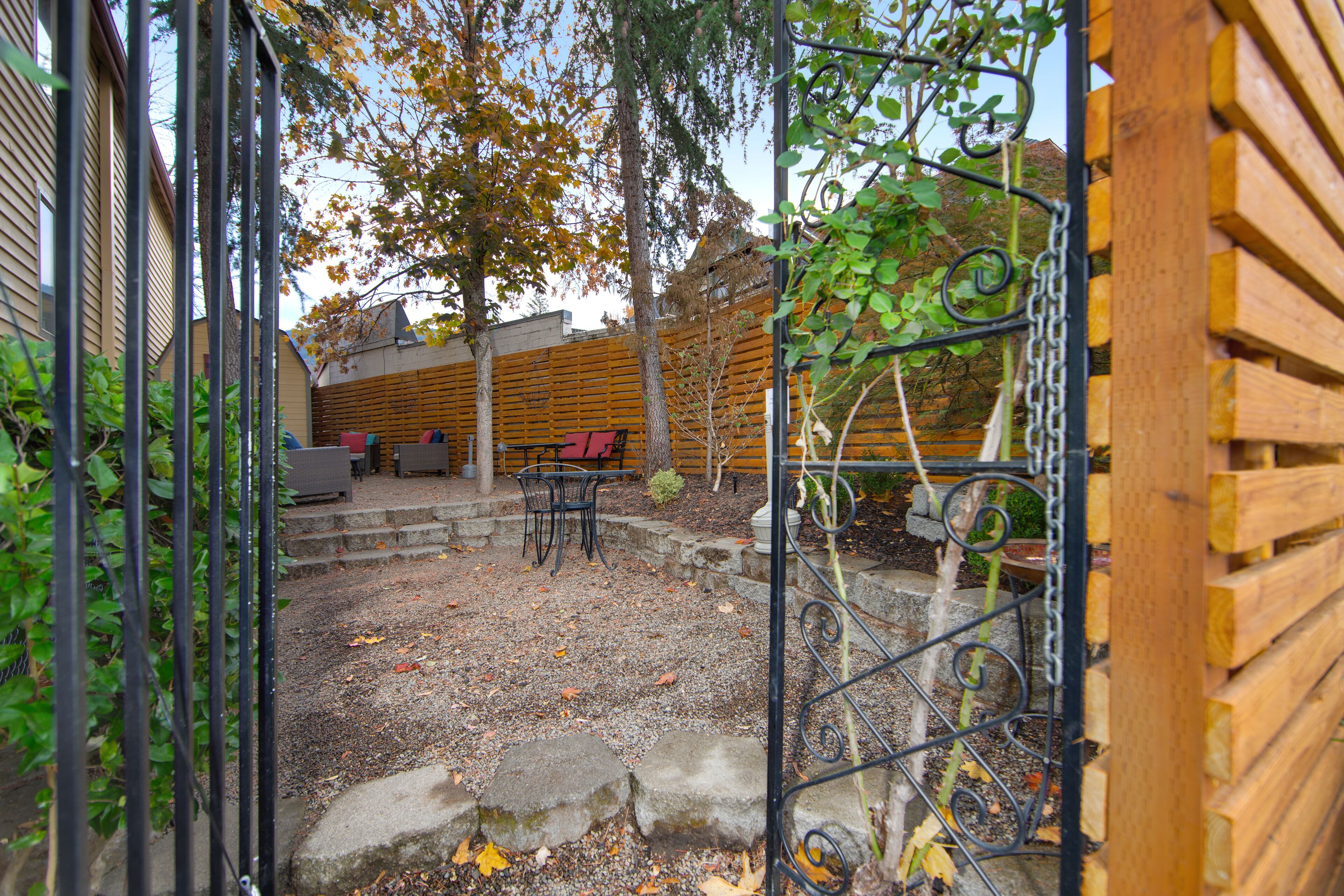 A wooden fence, a stone pathway, and a seating area with a table and chairs.