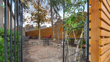 A wooden fence, a stone pathway, and a seating area with a table and chairs.