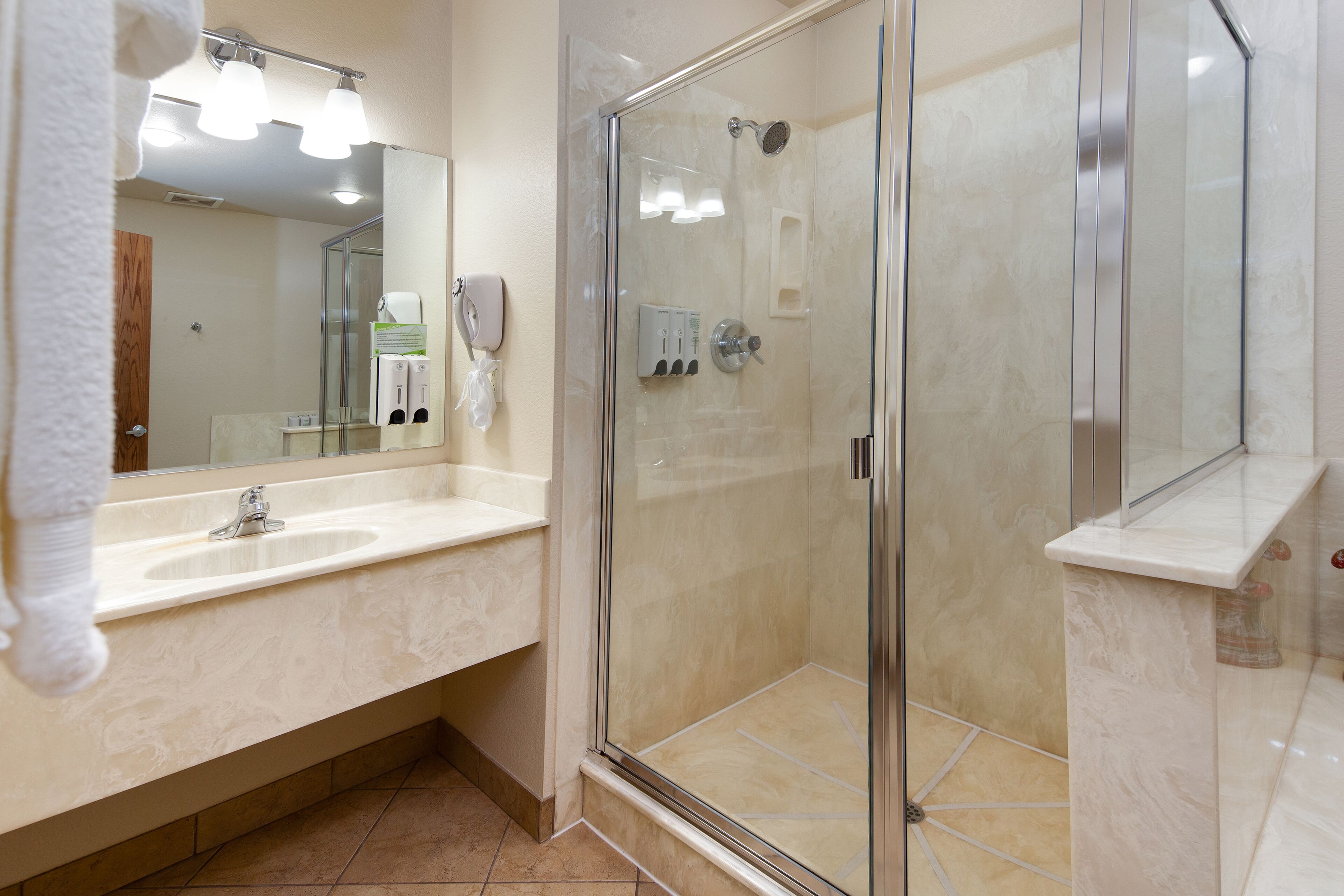 Un baño moderno con ducha de vidrio, un espejo grande y un lavamanos.