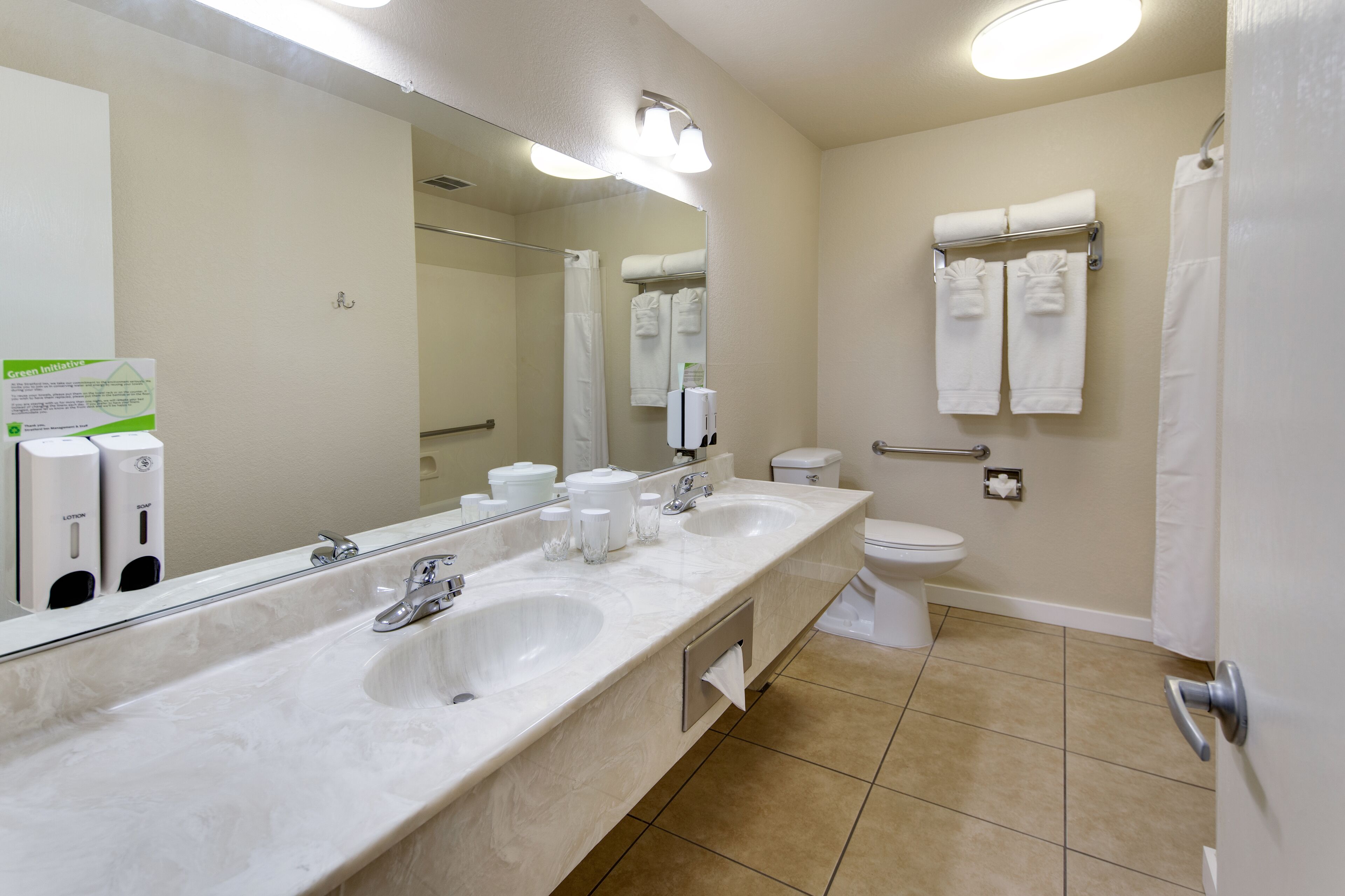 A modern bathroom with two sinks, a toilet, a shower, and a large mirror.