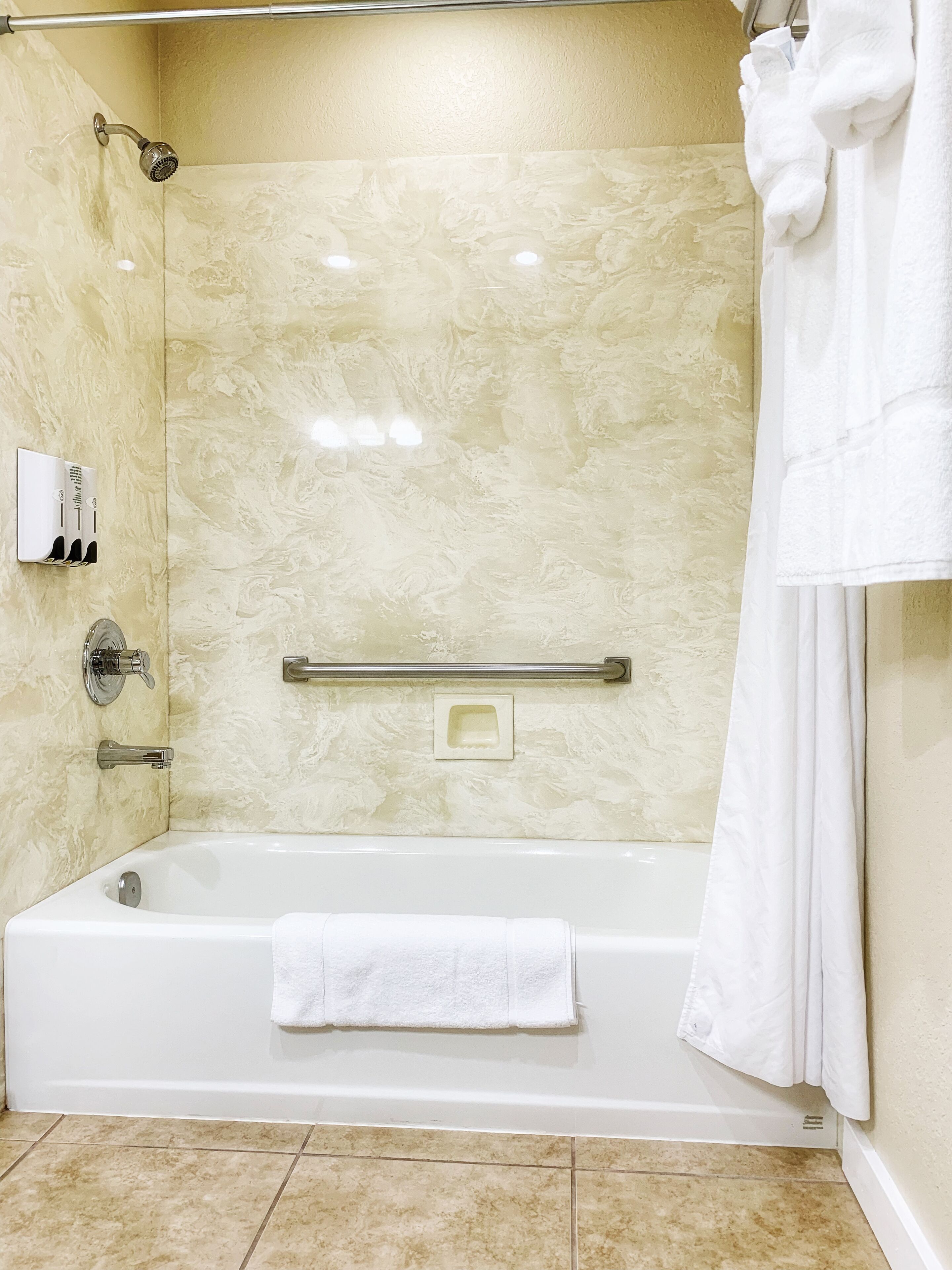 A modern bathroom with a bathtub, a shower, and a hand dryer.