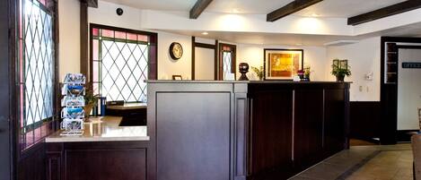A reception area with a dark wood reception desk, a clock, and a framed picture on the wall.
