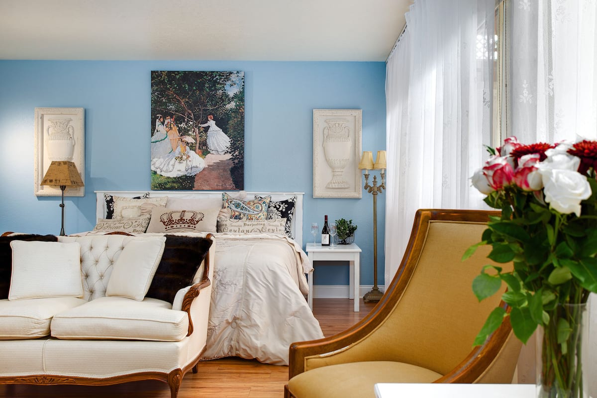 Um quarto com cama, sofá, poltrona e mesa de cabeceira.