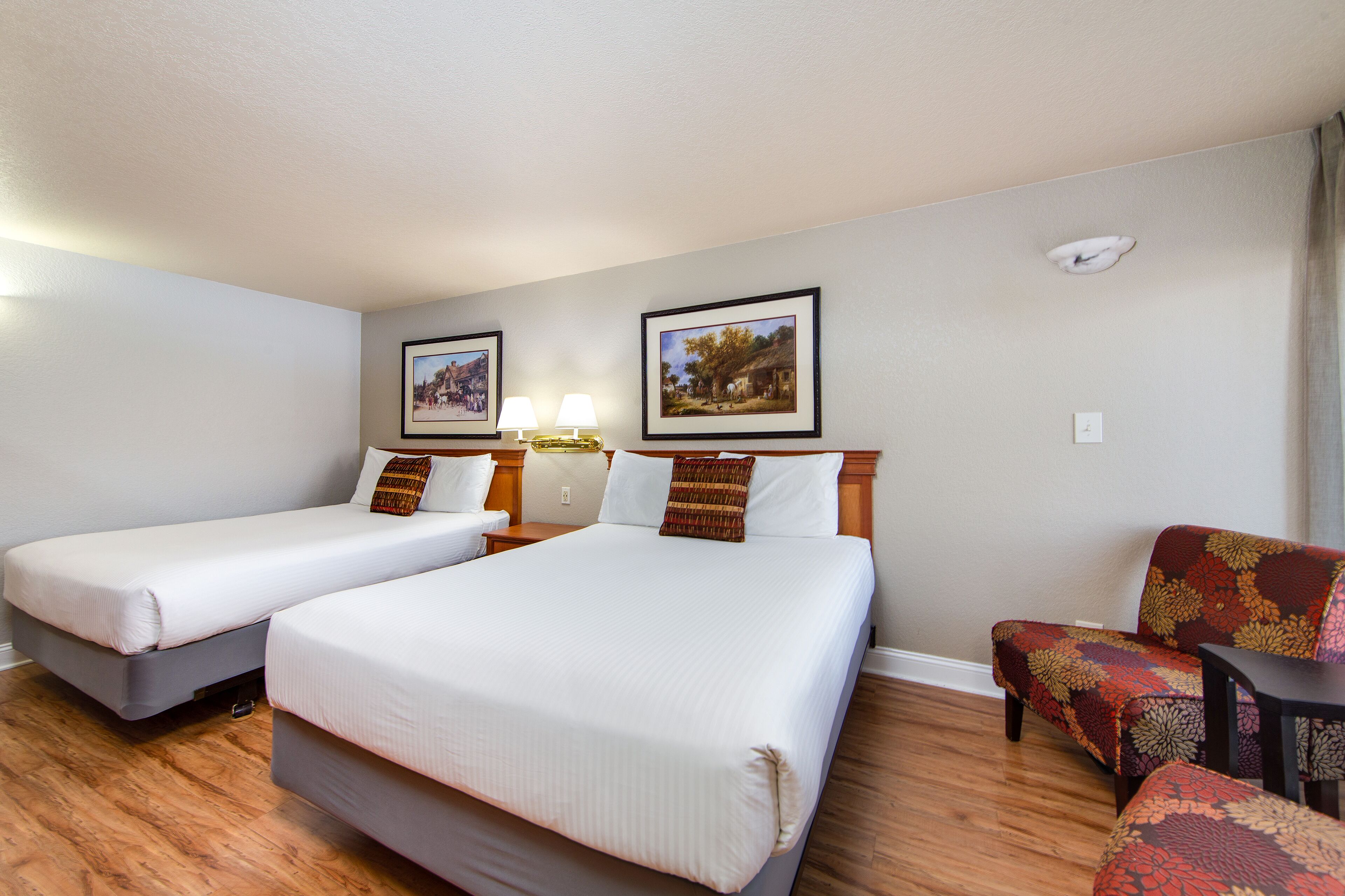 A hotel room with two single beds, a sofa, and two framed pictures on the wall.