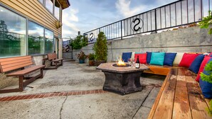 Un patio exterior con un brasero, asientos y plantas en macetas.
