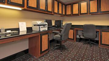 A small office with wooden cabinets, a desktop computer, and two office chairs.
