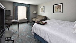 A hotel room with a bed, a desk, a chair, a TV, a lamp, and two framed pictures on the wall. - Hampton Inn Defiance (Defiance)