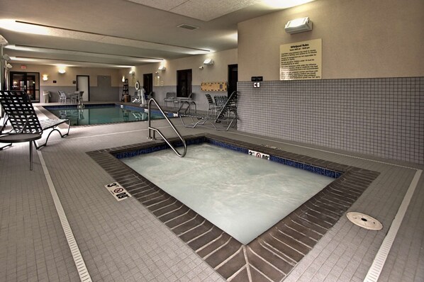 A swimming pool area with a tiled floor, a pool with a blue border, and a sign with rules.