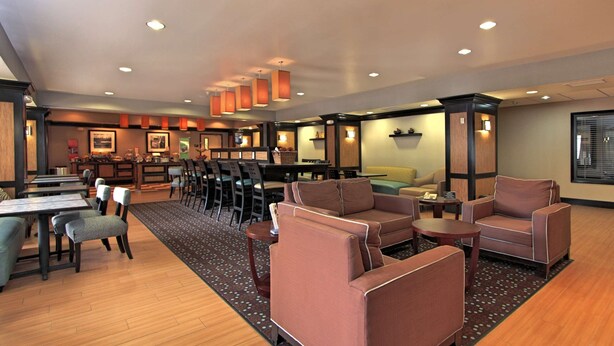 A hotel lobby with seating areas, a reception desk, and a bar. - Hampton Inn Defiance (Defiance)