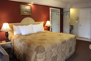 A hotel room with a large bed, two bedside lamps, a framed picture on the wall, and a door leading to a bathroom. - Country View Inn & Suites Atlantic City (Absecon)