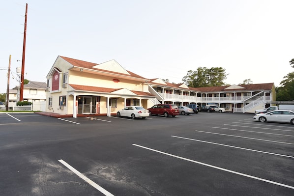 A motel with multiple units, a parking lot, and a few cars parked.