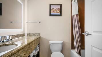 A bathroom with a granite countertop sink, a toilet, and a shower curtain.